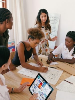 Group of women collaborating on a creative project in a modern office environment.